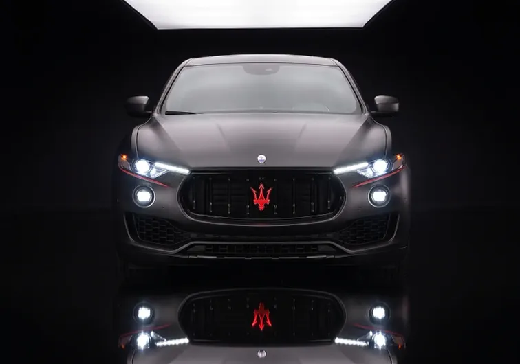 Vista frontale di una Maserati Levante nera opaca con fari accesi